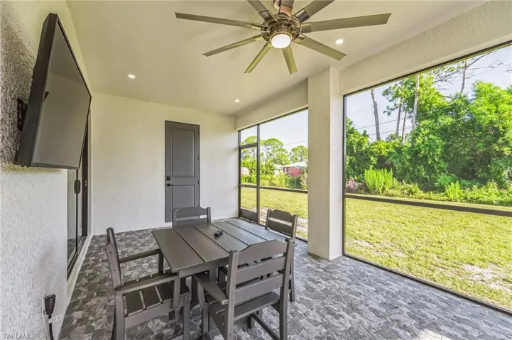 Screened lanai featuring a ceiling fan, recessed lighting, wall-mounted television, tiled flooring, and a solid panel door