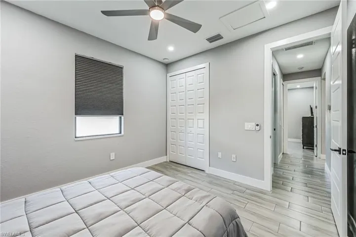 Spacious room featuring light-toned walls, a ceiling fan with integrated lighting, recessed lighting, and elegant wood-finish flooring