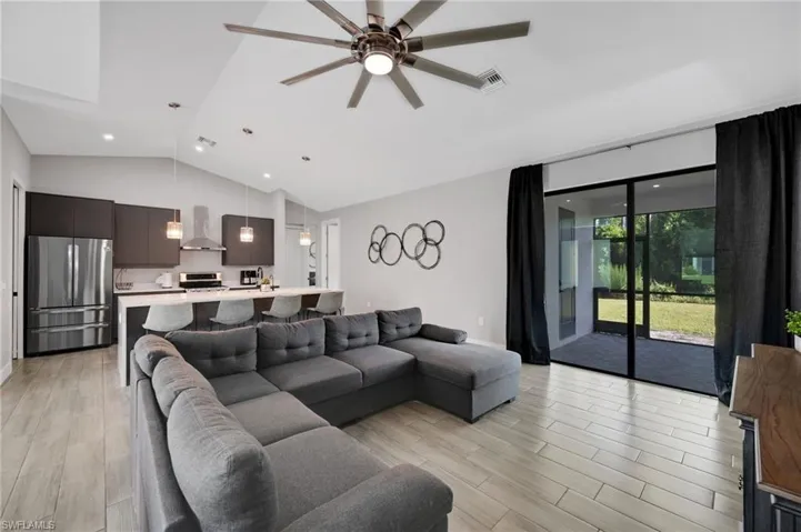 Open-concept living area featuring wood-finish flooring, vaulted ceilings, and recessed lighting