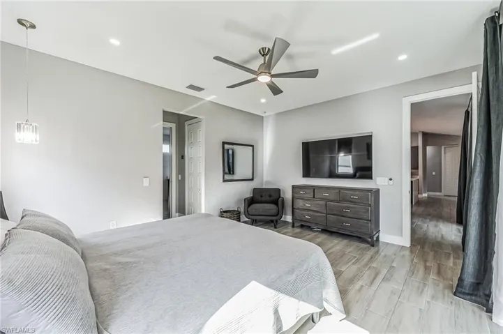 Spacious room featuring light-toned wood-finish tile flooring, a contemporary ceiling fan, recessed lighting, and a crystal pendant light fixture