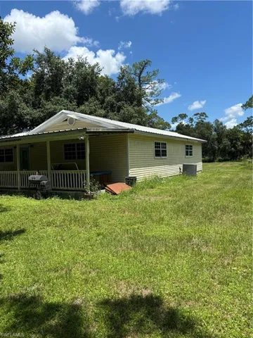 View of home's exterior with a metal roof, a lawn, and covered porch