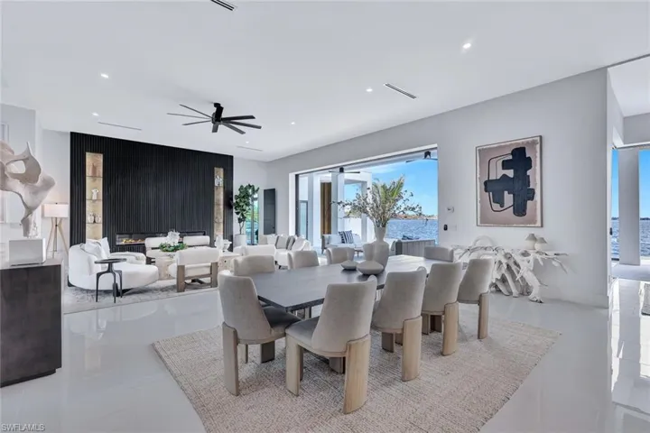 Dining space featuring ceiling fan, light tile patterned flooring, a water view, and a fireplace