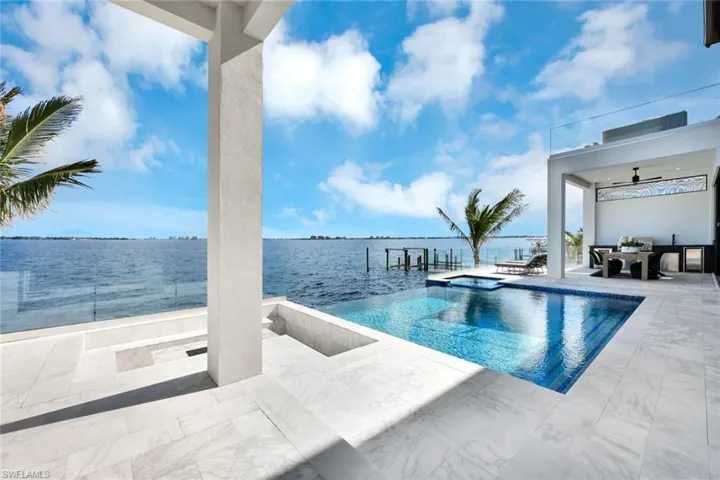 View of pool featuring an in ground hot tub, a water view, a patio, and ceiling fan
