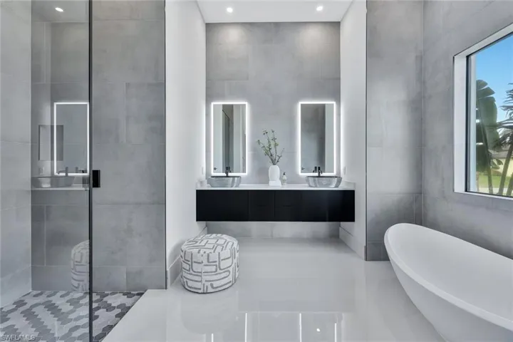 Bathroom with vanity, a wealth of natural light, plus walk in shower, and tile walls