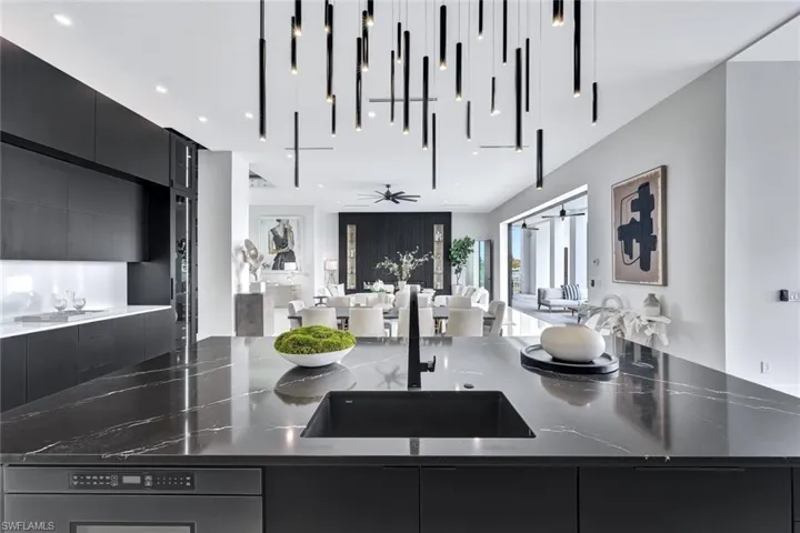 Kitchen with ceiling fan, dark stone countertops, and sink