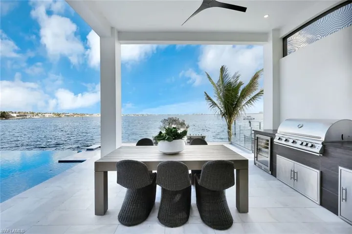 View of patio featuring ceiling fan, a water view, exterior kitchen, and grilling area