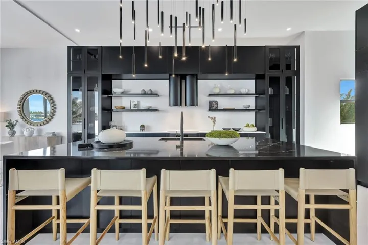 Kitchen featuring a breakfast bar, dark stone countertops, a spacious island, and sink