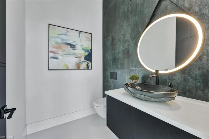 Bathroom featuring tile patterned flooring, vanity, toilet, and tile walls