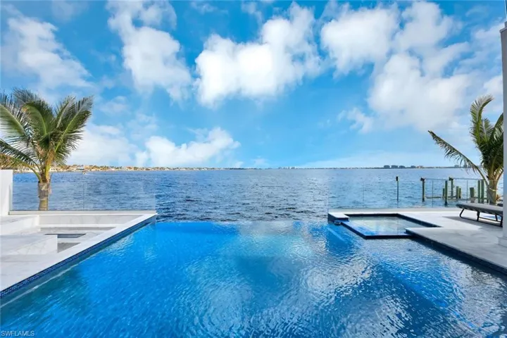 View of pool with a patio area, an in ground hot tub, and a water view