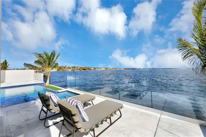 View of swimming pool with an in ground hot tub, a water view, and a patio