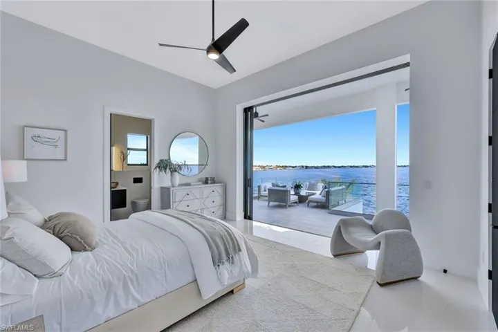 Tiled bedroom with a water view and ceiling fan