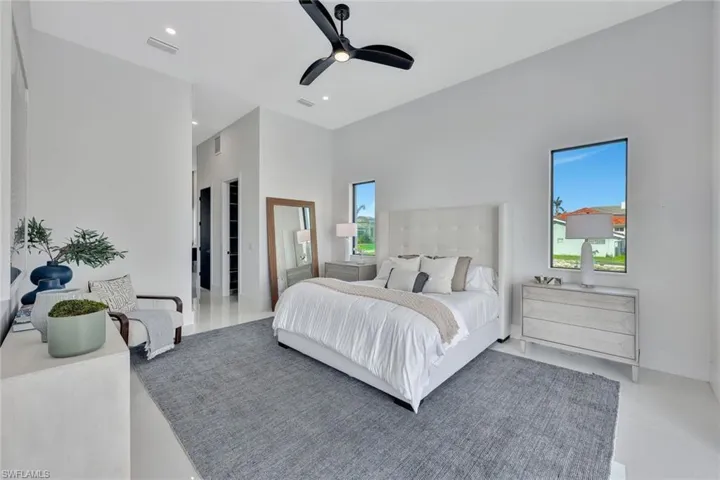 Bedroom featuring tile patterned flooring, ceiling fan, and a high ceiling