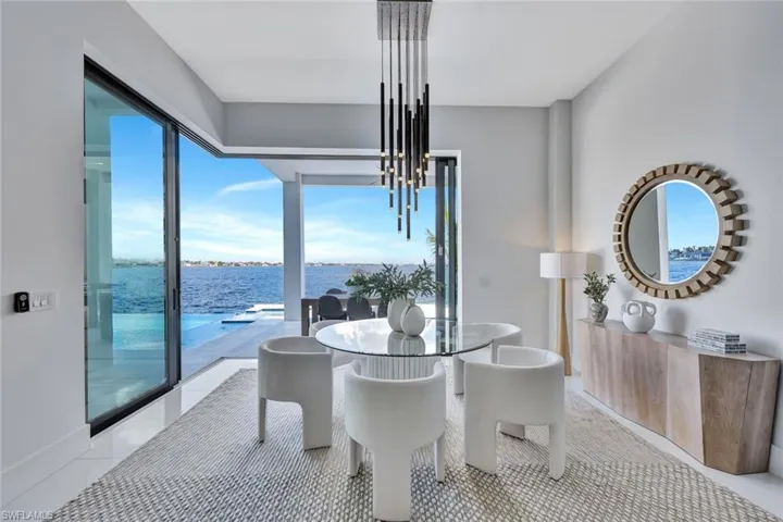 Dining space with a healthy amount of sunlight, a water view, light tile patterned floors, and a notable chandelier