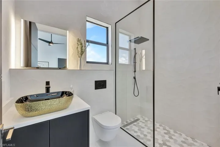 Bathroom with tasteful backsplash, vanity, tiled shower, tile walls, and toilet