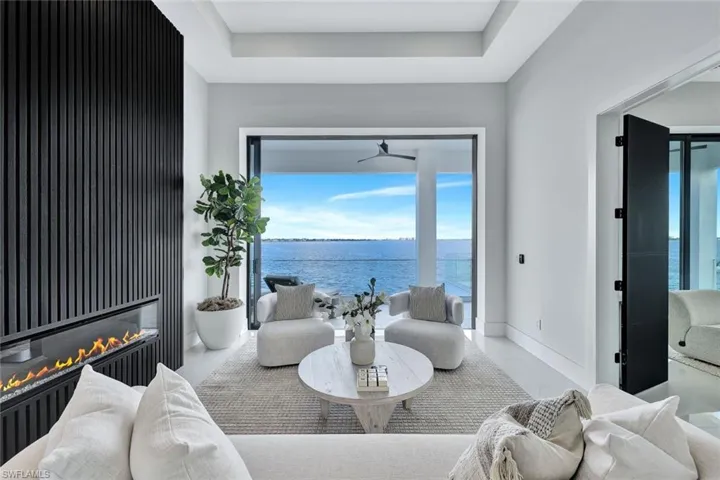Living room with a raised ceiling, ceiling fan, and a water view