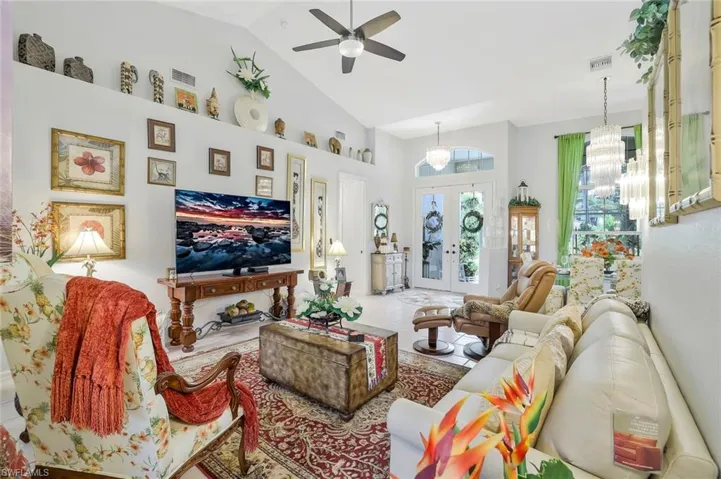 Living room featuring high vaulted ceiling, a chandelier, french doors, ceiling fan, and tile patterned floors