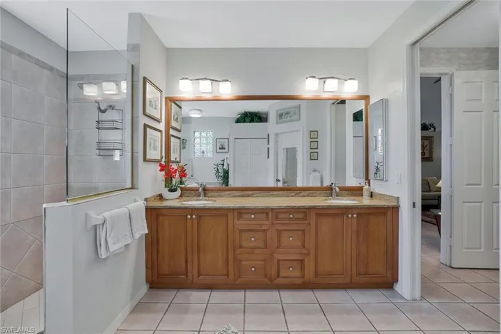 Bathroom featuring walk in shower, double vanity, and light tile patterned flooring