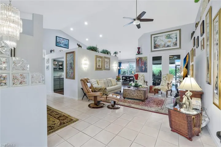 Living room featuring high vaulted ceiling, light tile patterned floors, ceiling fan, recessed lighting, and a chandelier