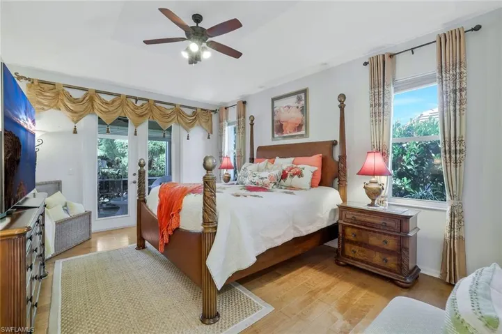 Bedroom with multiple windows, wood finished floors, access to outside, and ceiling fan