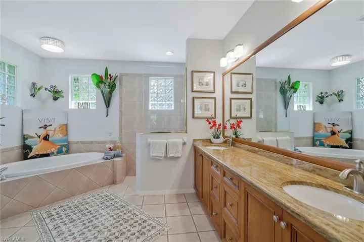Full bathroom featuring a garden tub, double vanity, light tile patterned floors, and walk in shower