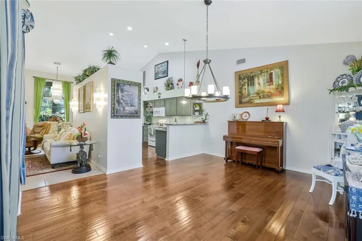 Dining space with a chandelier, dark wood-style flooring, high vaulted ceiling, and recessed lighting