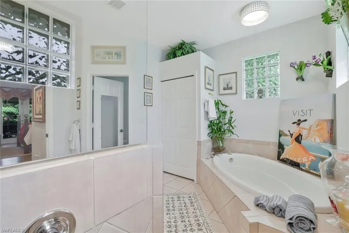 Bathroom featuring a garden tub, light tile patterned floors, and a closet
