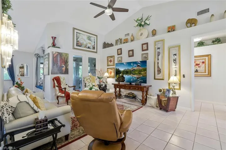 Living area featuring light tile patterned floors, high vaulted ceiling, ceiling fan, and french doors