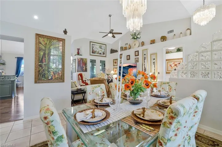 Dining space featuring light tile patterned floors, a ceiling fan, a chandelier, and high vaulted ceiling