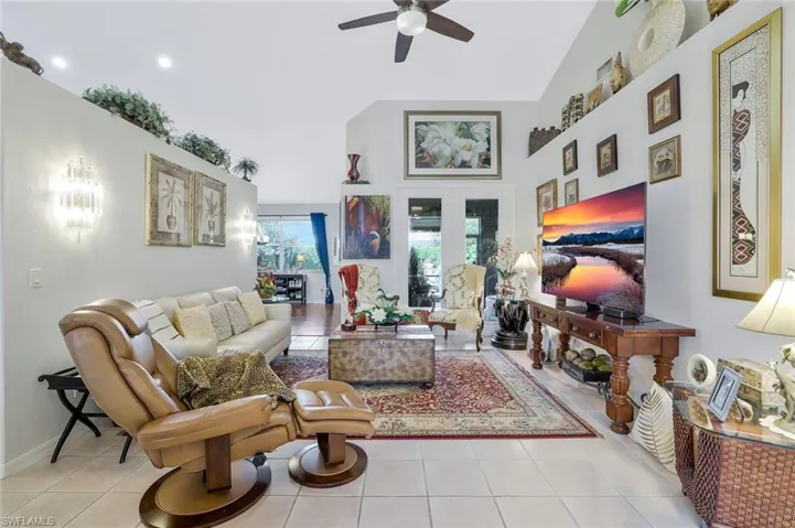 Living area featuring tile patterned floors, ceiling fan, and high vaulted ceiling
