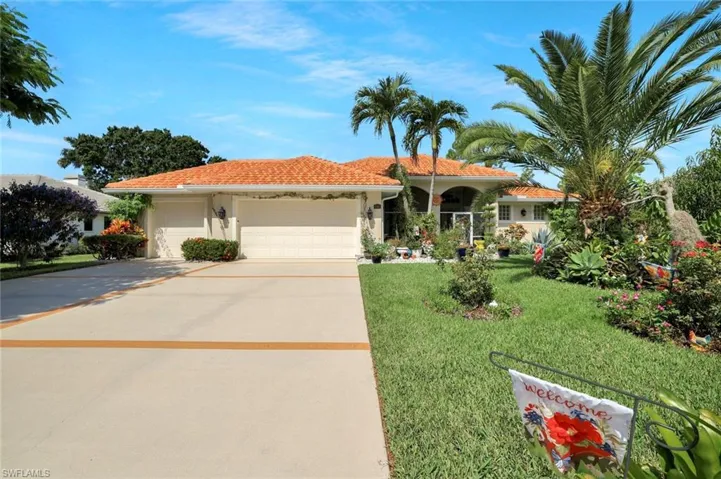 Single story home featuring an attached garage, driveway, a front yard, stucco siding, and a tile roof