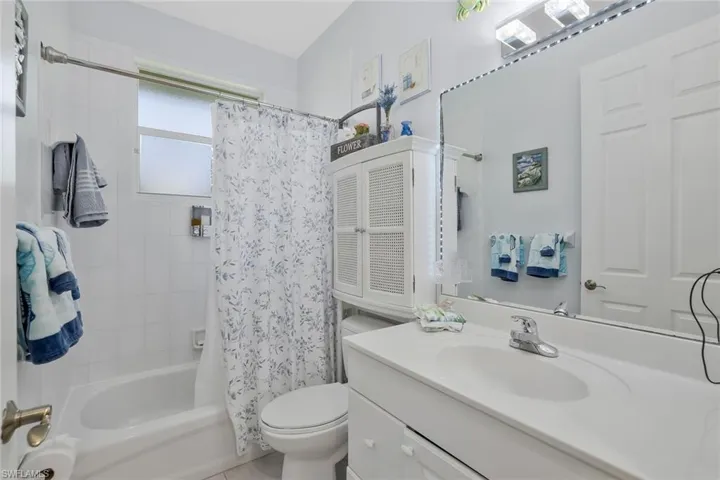 Bathroom featuring vanity, shower / bath combo with shower curtain, and light tile patterned flooring
