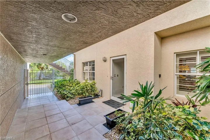 View of exterior entry with a patio area, stucco siding, and a gate