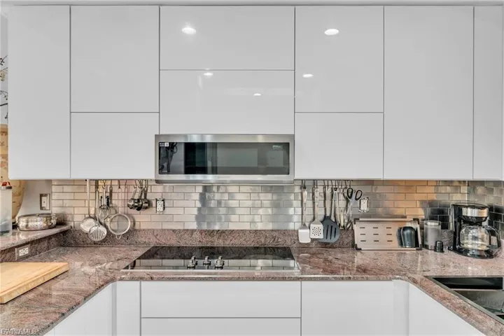 Kitchen featuring light stone countertops, white cabinets, and modern cabinets