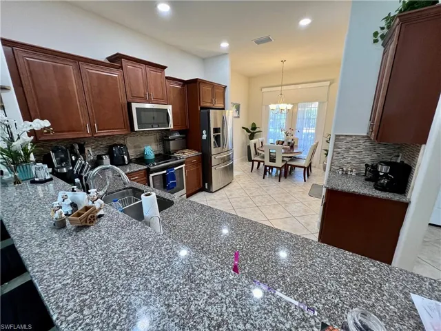 Kitchen featuring granite counters, upgraded wood cabinets, a tiled backsplash, reverse osmosis, stainless steel appliances and a large pantry