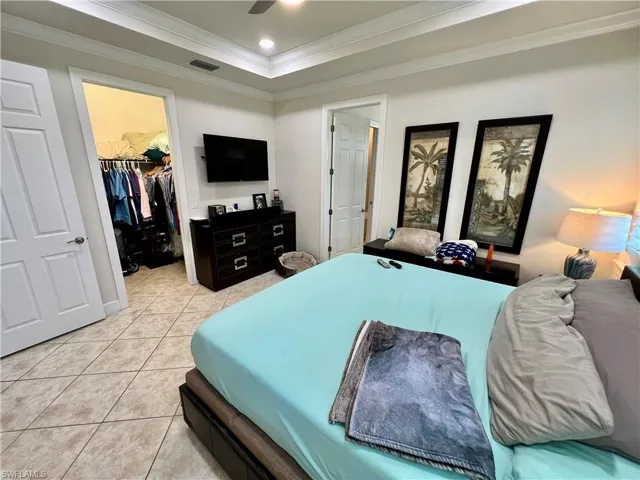 Master bedroom boasting a tray ceiling dressed with crown molding, LED lighting and custom plantation shutters
