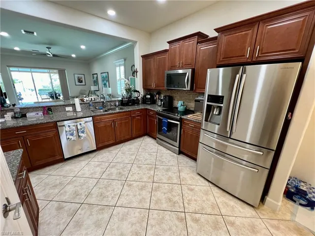 Kitchen featuring granite counters, upgraded wood cabinets, a tiled backsplash, reverse osmosis, stainless steel appliances and a large pantry