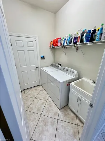 Laundry room connected with garage that includes washer and dryer, utility sink and an alarm system