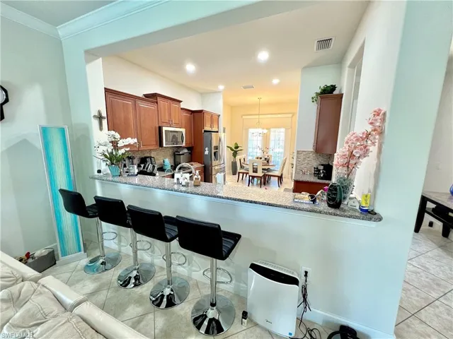 Kitchen featuring granite counters, upgraded wood cabinets, a tiled backsplash, reverse osmosis, stainless steel appliances and a large pantry