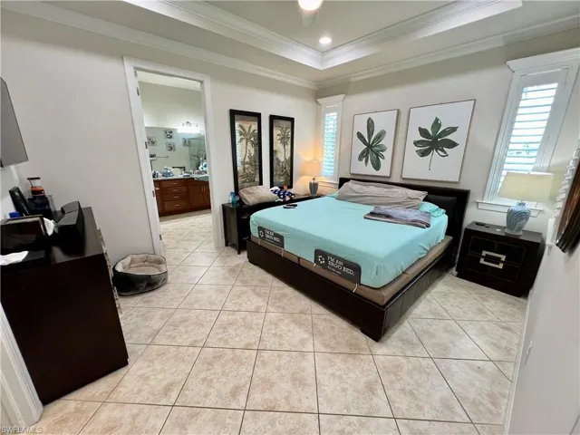 Master bedroom boasting a tray ceiling dressed with crown molding, LED lighting and custom plantation shutters