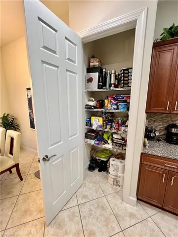 Kitchen featuring granite counters, upgraded wood cabinets, a tiled backsplash, reverse osmosis, stainless steel appliances and a large pantry