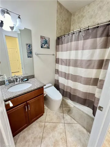 Guest bathroom with granite counters, a shower tub combo and a Woodbridge one piece smart toilet