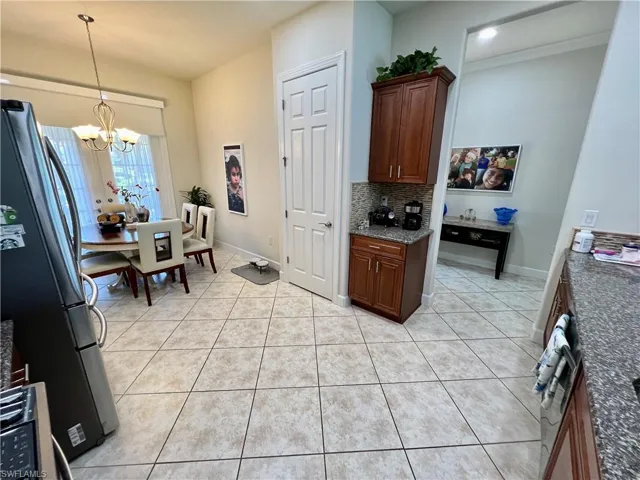 Kitchen featuring granite counters, upgraded wood cabinets, a tiled backsplash, reverse osmosis, stainless steel appliances and a large pantry