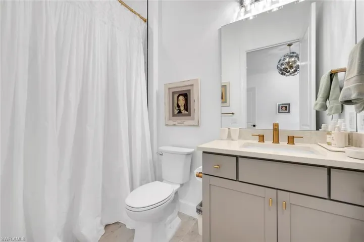 Bathroom with vanity, toilet, and curtained shower