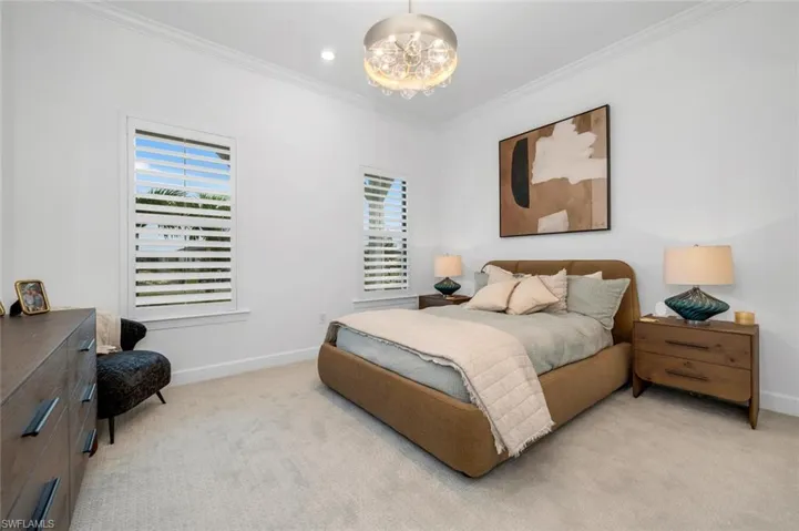 Bedroom featuring multiple windows, light colored carpet, and crown molding