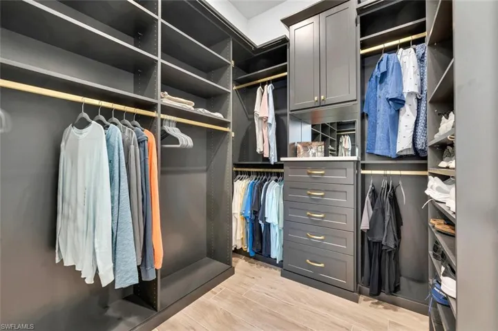 Walk in closet with light hardwood / wood-style flooring