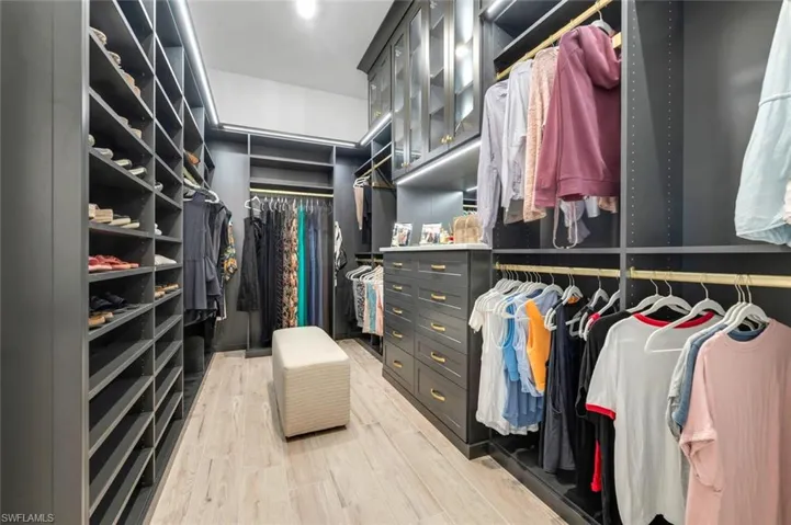 Walk in closet with hardwood / wood-style floors