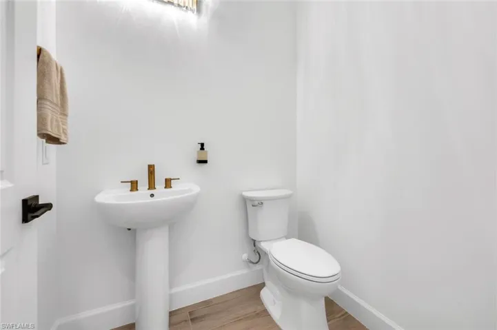 Bathroom with toilet, sink, and hardwood / wood-style floors