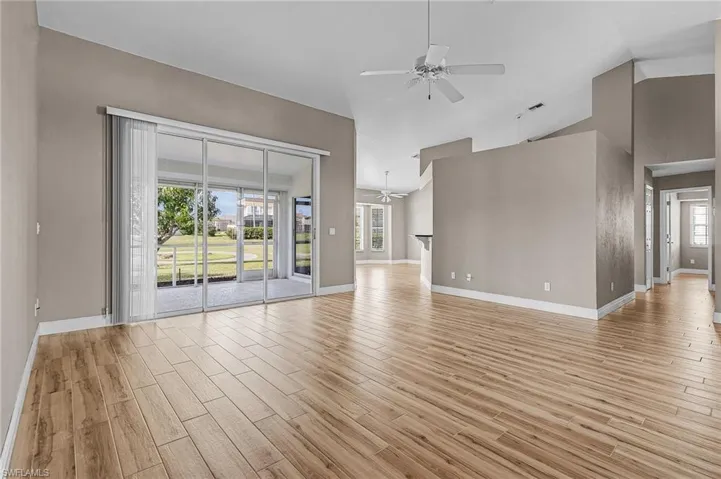 Unfurnished living room featuring ceiling fan, light hardwood / wood-style flooring, and vaulted ceiling