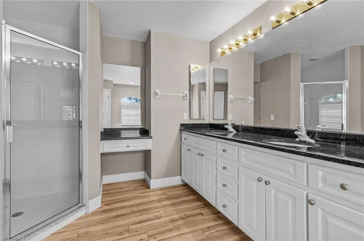 Bathroom featuring vanity, wood-type flooring, and a shower with door