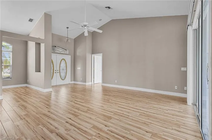 Unfurnished living room featuring light wood-type flooring, high vaulted ceiling, and ceiling fan